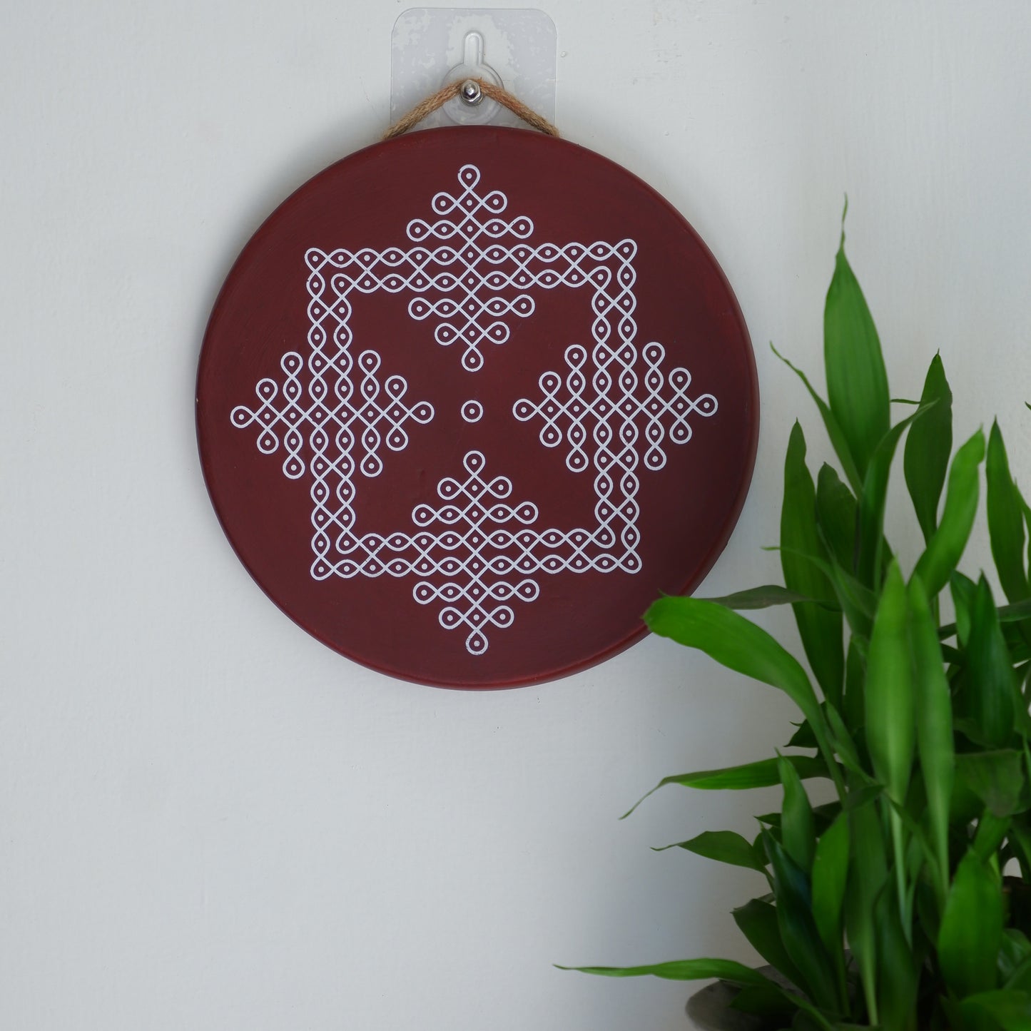 A wall decor image of our 8 inch Maroon Traditional South Indian Sikku Kolam Terracotta Wall Plates for Indian Homes