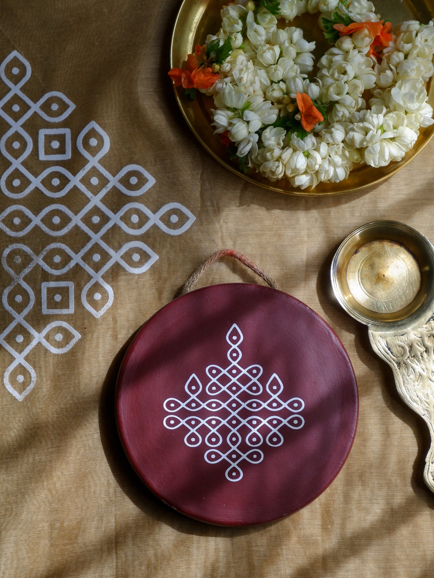 flat lay image of 6 inch Maroon Traditional South Indian Sikku Kolam Terracotta Wall Plates