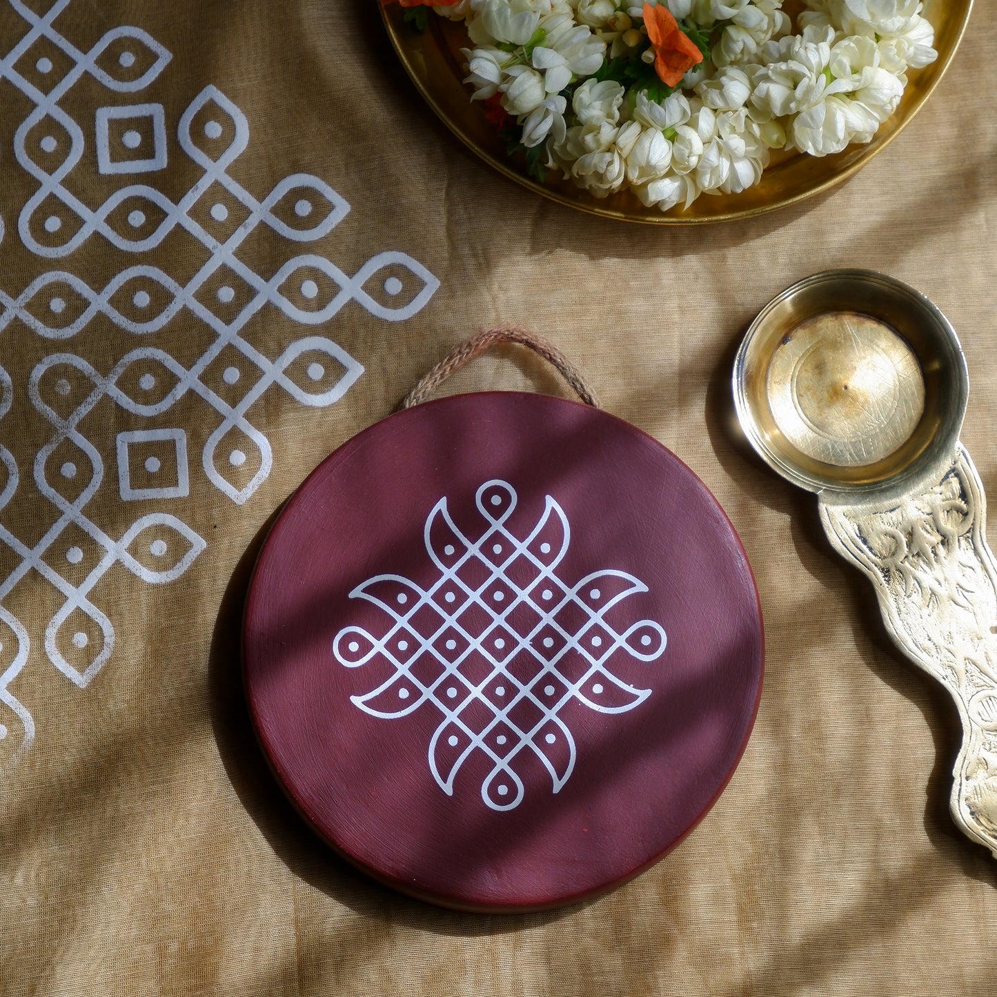 flat lay image of 6 inch Maroon Traditional South Indian Sikku Kolam Terracotta Wall Plates