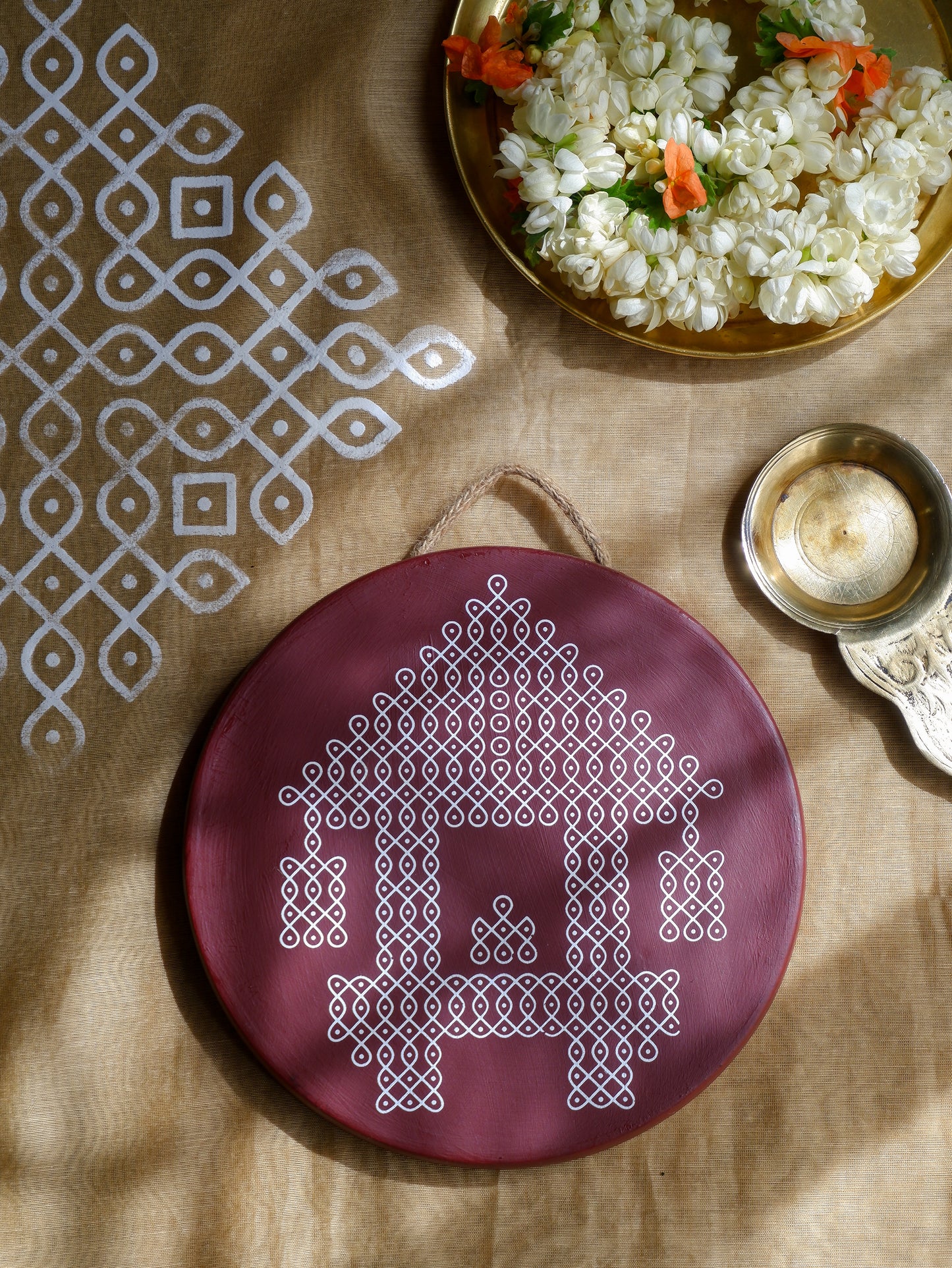 Flatlay image of our 8 inch Maroon Ther Traditional South Indian Sikku Kolam Terracotta Wall Plates for Indian Homes