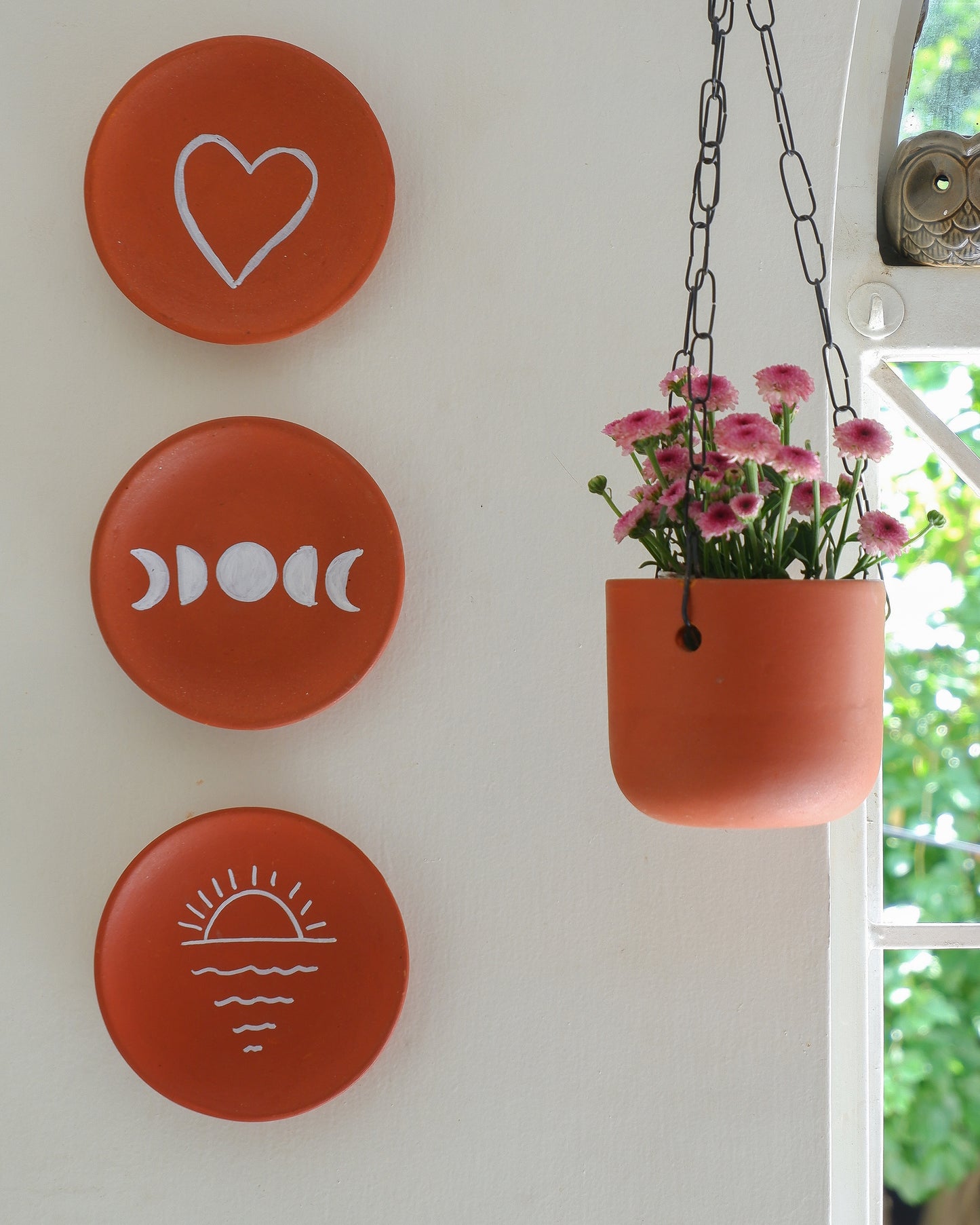 DIY terracotta wall plates hung on a white wall in a creative arrangement painted