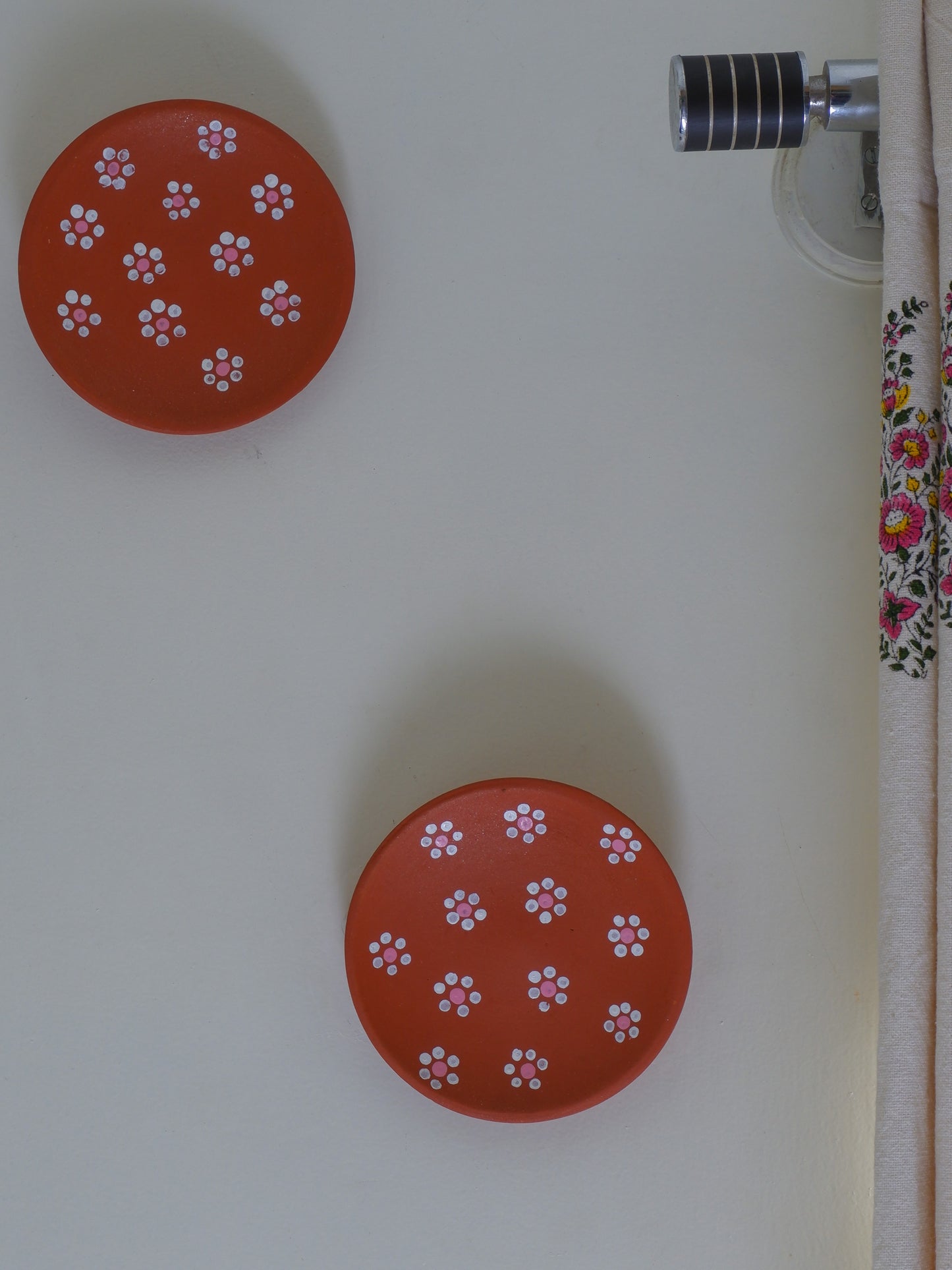 DIY terracotta wall plates hung on a white wall in a creative arrangement ready to be painted