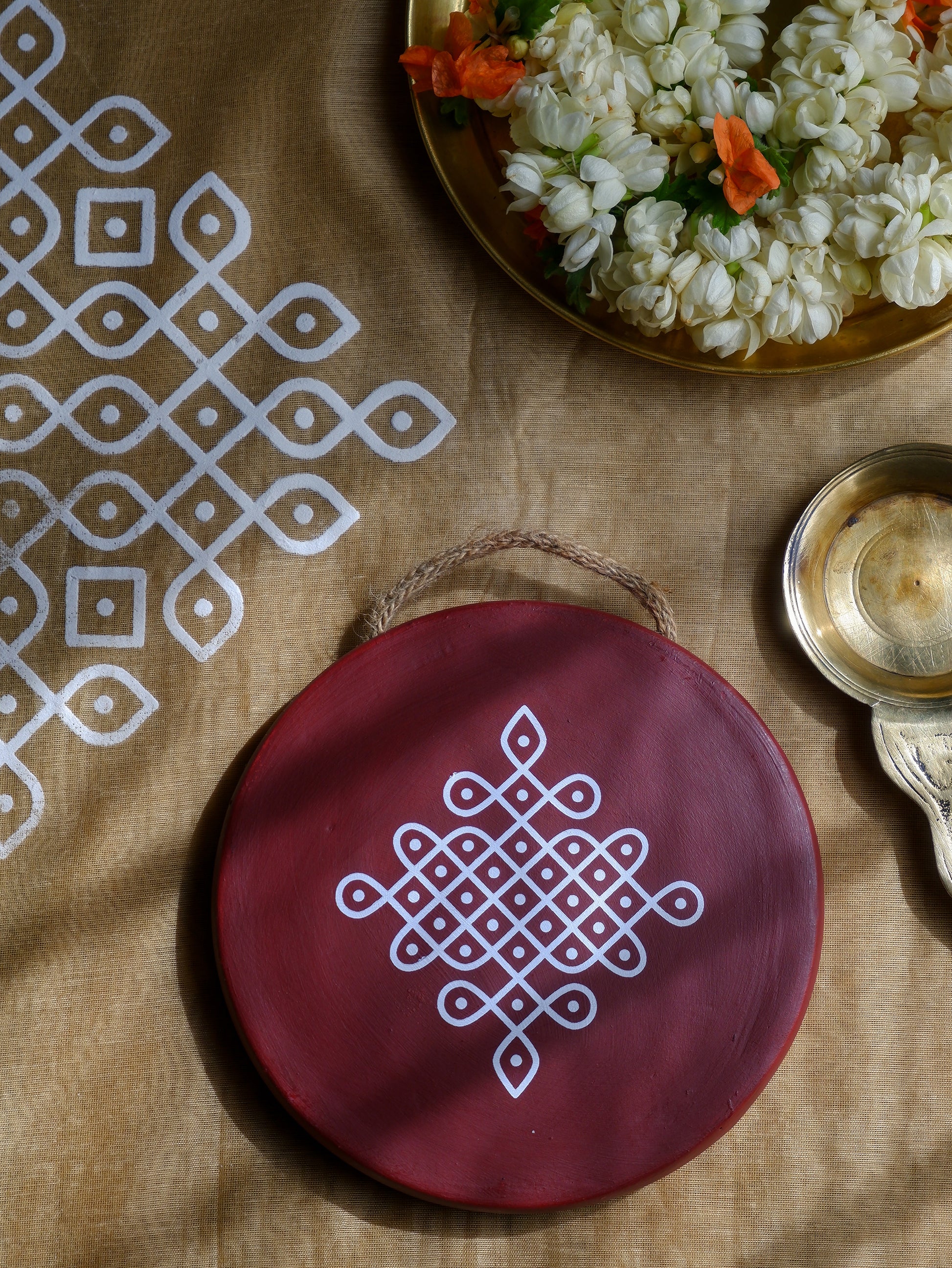 flat lay image of 6 inch  Maroon Traditional South Indian Sikku Kolam Terracotta Wall Plates 