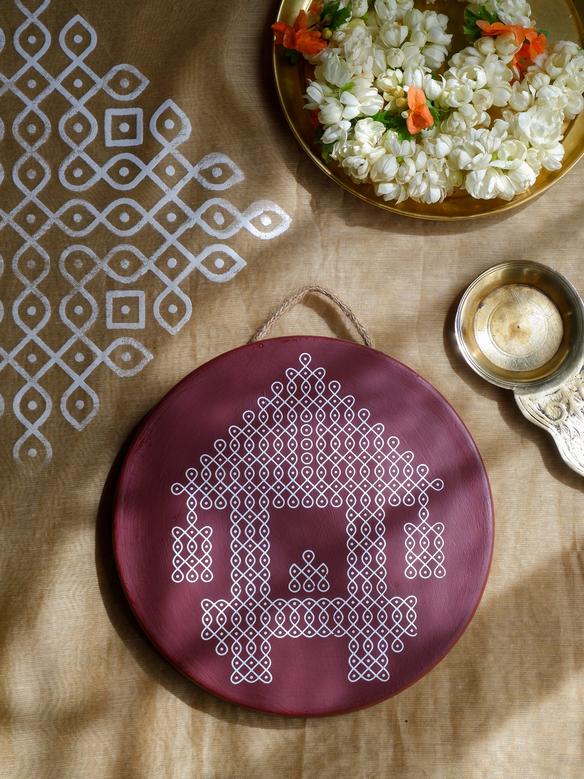 Flatlay image of our 8 inch  Maroon Ther Traditional South Indian Sikku Kolam Terracotta Wall Plates for Indian Homes